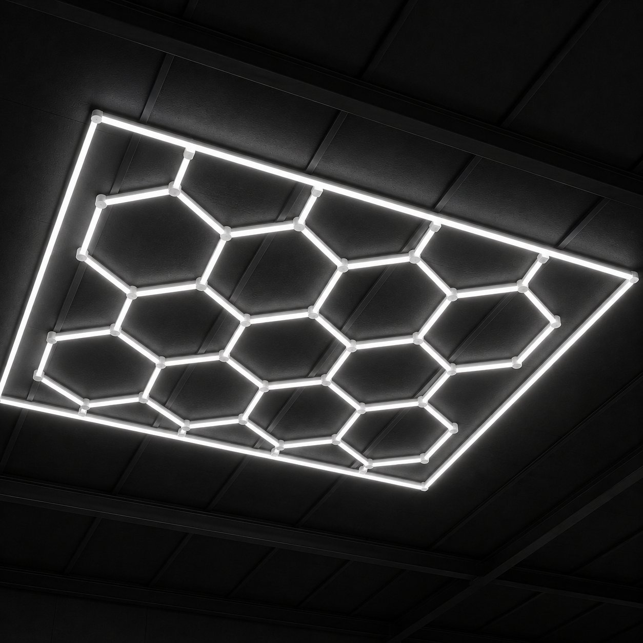 Panel LED hexagonal CorsaLux Hexa Pro encendido en blanco neutro sobre el techo de un taller